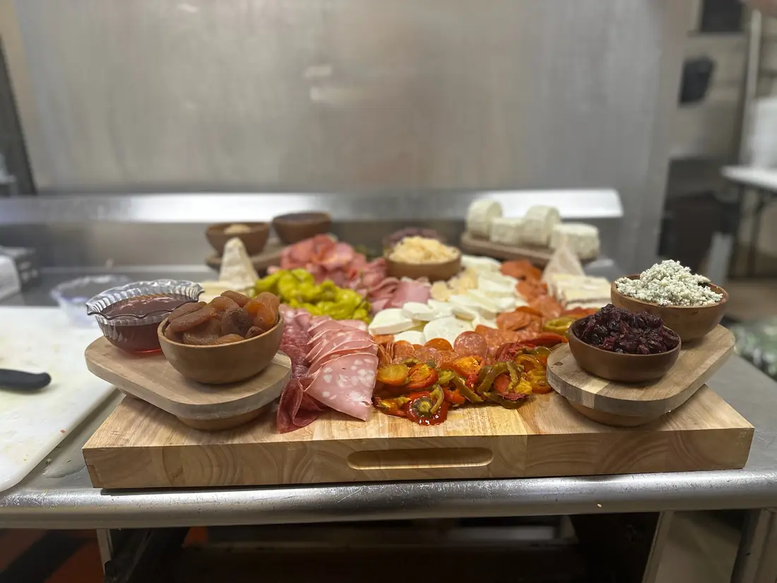 Charcuterie board with cured meats, fresh mozzarella, blue cheese, peppers and dried fruit on a wooden board, food photography by chef J.O. King
