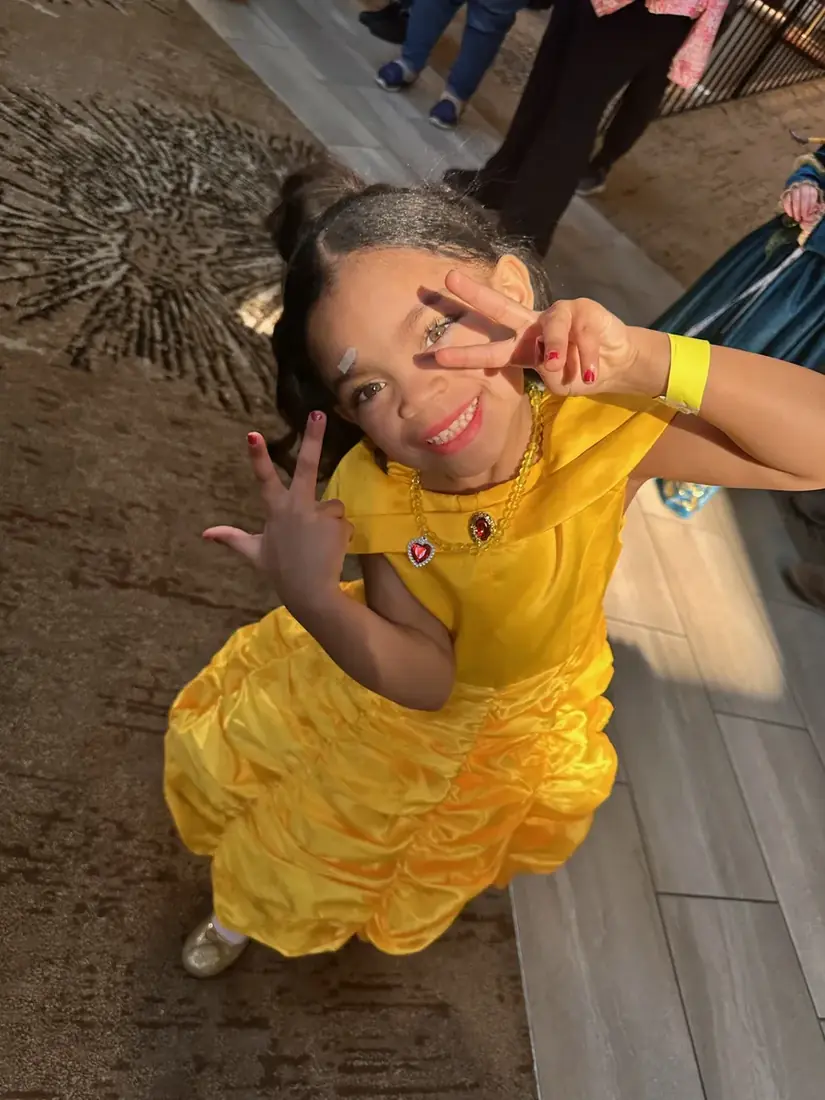 Princess Liv in a yellow gown throwing up peace signs at the Princess Ball, family and character event photography by Pixel Perfect Visuals